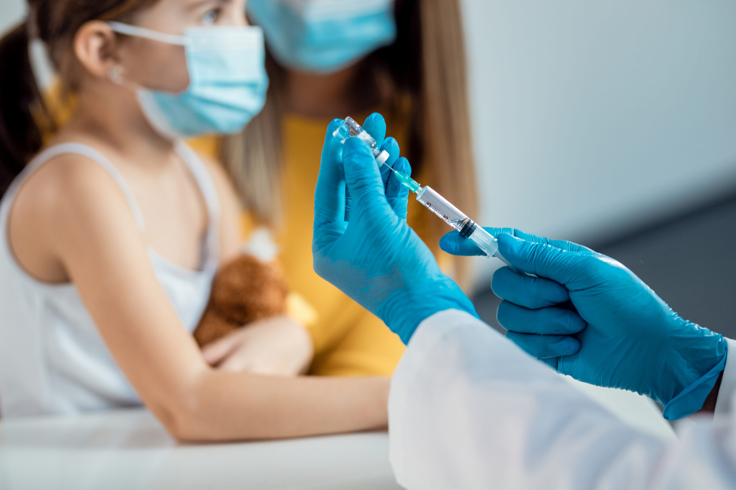 Close-up of doctor preparing a syringe for child's vaccination.